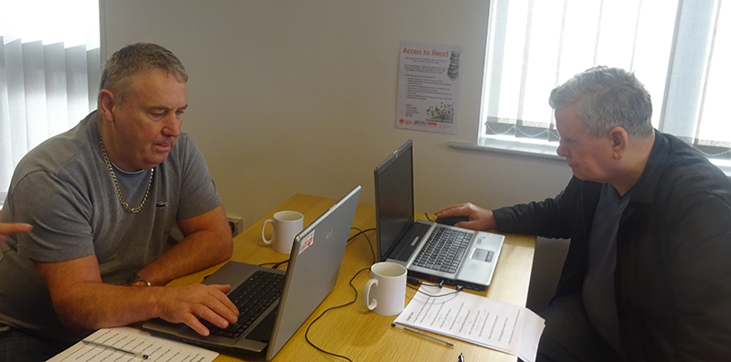 Two men at desks using laptops. 