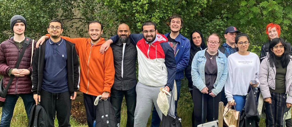 Photograph of eleven people standing outside smiling and laughing. 